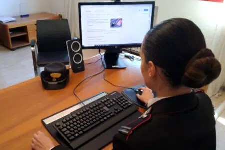Raffica di truffe online a Siena e Monteroni: 5 denunciati dai Carabinieri Maresciallo dei Carabinieri effettua indagini al computer