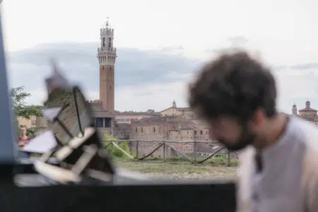 Siena Jazz, bando per direttore artistico-didattico Siena Jazz, Corsi Formazione Musicale, pianista con veduta Siena sullo sfondo