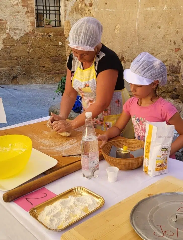 "Appicicchia", gara dei pici a Castelmuzio, donna e bambina durante la preparazione dei pici