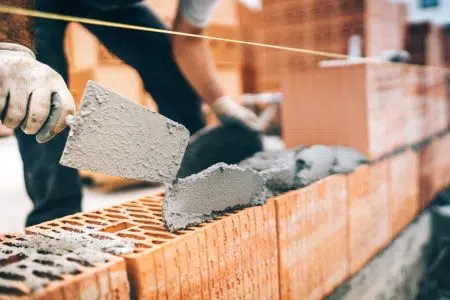 Sicurezza sul lavoro, crescono gli infortuni. Edilizia, muratore al lavoro in cantiere, mattoni