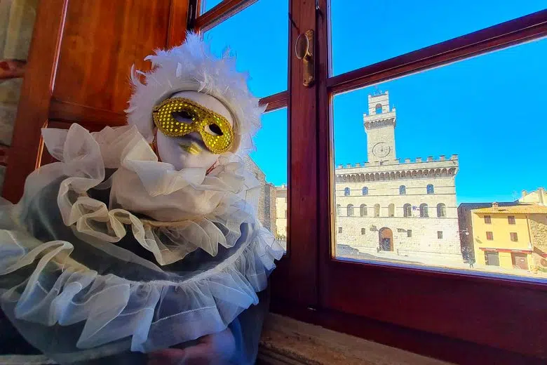 Montepulciano: tutti gli eventi per festeggiare il Carnevale Carnevale a Montepulciano, persona mascherata con Palazzo Comunale sullo sfondo