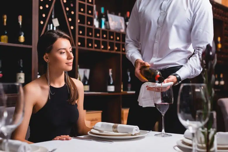Donna al ristorante, sommelier serve il vino